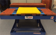 Figure 1. This is the transfer station set up at Human Engineering Research Laboratories for all testing procedures. The transfer station is operated by hydraulic scissor lift, which is located in the back of the station. It has a yellow cushion on top of it for subjects to transfer to. It also has two blue side guards on either side of the cushion. 