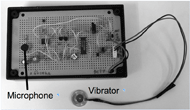 This figure shows the photo image of prototype drive unit with a vibrator and a microphone. The circuit board is housed in a case.