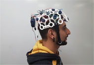 EEG headset made for OpenBCI Project on a subject’s head. This headset is an example of cost-effective and easy-to-use EEG systems. One of the reasons for the lower cost is the 3D printed headset. The headset look like a biking helmet with a strap that goes under the chin. It is also wired, as opposed to the EEG headset form Emotive. The design is bulkier than Emotive’s headset, and seems comparable to G.tec’s EEG system. Although the G.tec system uses a fabric-made cap, instead of 3D printed helmet. Another difference between this EEG system and the other two is that it uses dry electrodes.
