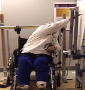 Image shows a participant from the pilot study leaning sideways over the wheelchair to reach for a vertical plane. 