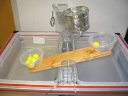 Figure 5 shows the wood teeter totter.  A whole has been bored in the exact center through which a threaded rod is run.  The rod is bolted to two plastic pieces mounted to another piece of plastic that is bolted to the table.