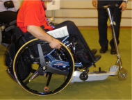 Picture of manual wheelchair user demonstrating mounting of ultra light weight wheelchair onto the scooter.
