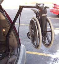 This photograph shows the Wheelchair being lifted into the car.  The main post of the lifting system is located in a corner close to the rear bumper.