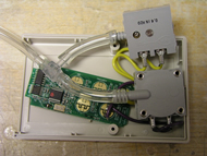 This photo shows a completed modification for sip & puff control of an ipod. Two pneumatic switches are soldered to the AirClick system board, with oxygen tubing extending out of the plastic encasement to hook to a gooseneck for ease of access.