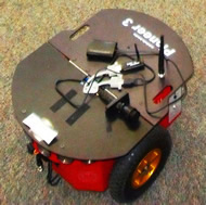 Image shows the Pioneer 3 robot we are using.  Notice the round sonar sensors along the top of the front face. 