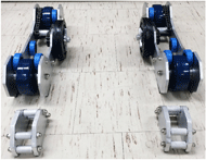 Photographs of the assembled system include two separate roller units and two front wheel support stands, with visible details including blue drive and lateral support wheels, two chain drives in each unit, and secure attachment of small barbell plates. 