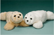 Picture shows two PARO robots next to each other. These robots look like seals, and are designed to interact and react to touch and other stimuli. 