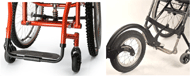 Two side by side images, one showing a standard manual wheelchair footrest with no attachment, and one showing a manual footrest with a passive front attachment clamped onto it. It attaches at the center of the footrest and and lifts up the caster wheels.  