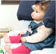 An infant seated in a car seat with a position tracker on her forehead during the A-not-B experiment.