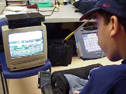 This is a photograph of the same student reading play options on the TV for a PlayStation 2 football game.