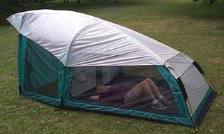 Photo of the side view of the combination vestibule/tent. Inside a person is lying on their back in the sleeping area. 
