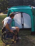 Photo of a person with a wheel chair opening the door to the combo and exposing the inside of the vestibule and the inner door to the sleeping area. 