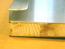 Image shows a close-up of the perpendicular edge of an aligner tray with a lip that is parallel to the tray surface.  The aluminum edges are rounded at the end to prevent injuries.