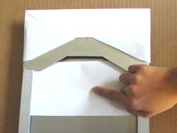 Image shows the author pushing a piece of trifolded document along the aligner tray of the 9x 4 envelope inserting aid using her index finger. An envelope is positioned over the channel of the device.