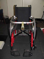 This figure shows the lap bar mounted to a wheelchair and a sensor module mounted to the lap bar. One photo shows the bar closed and one photo shows the bar opening and rotating about the clamps which are attached to the backrest of the chair.