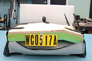 This figure shows a complete fracture of the seatpan of planar seat B after testing on a commercial wheelchair base.  The fracture is slightly to the left of the seatpan centerline and penetrates all layers of plywood at the front edge of the seat and several layers as it extends rearward down the length of the seatpan.