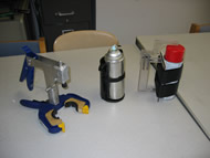 This photo shows 3 prototype devices that would allow a man with partial finger amputations to use a spray can.  The first uses a pistol grip, the second is a holder to allow him to his middle finger, the third device allows him to use his remaining thumb motion. 