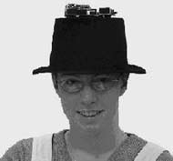 This is a photograph showing the instrument attached to the top of a top hat, which is being worn by an author.
