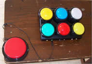 This photograph shows the dashboard with six colored buttons corresponding to the six watering stations. A big red switch is plugged into one of six color coordinated jacks. 