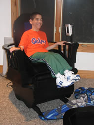 Image shows a photo of our client, a 13-year-old male smiling while sitting on the completed chair.