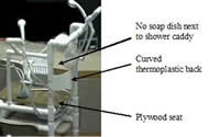 This photo shows the prototype for the bath chair. The prototype differs from the final product in the following ways. The back of the chair is a curved piece of thermoplastic, and the seat is made of plywood. Only one bath sponge is mounted on the top rail for head-washing, and only two bath sponges are mounted on the back post for back-washing. In addition, there is no soap dish accompanying the shower caddy.  