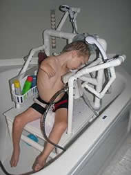 This photo shows our client using the bath sponges on the top rail of the chair to wash his hair. He can reach the sponges with his hand to apply shampoo to them, and then he rubs his head against the sponges to wash his hair. This eliminates the need for him to use his hands to wash his hair directly. 