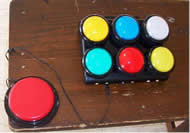 This photograph shows the dashboard with six colored buttons corresponding to the six watering stations. A big red switch is plugged into one of six color coordinated jacks. 
