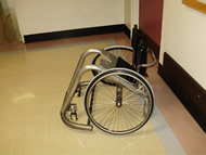 This photograph shows the side view, which shows that the wheel is placed near the back to move the center of mass of the chair, and how the chair sits on the caster wheels. 