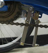 	Photo 3 is a closer view of the modified brakes. The two metal brackets shown were used as extensions: the left-most bracket is the brake lever extension and the right-most bracket is the brake cable fastener extension. This photo shows that the lever extension is secured to the original brake lever using two screws and the cable fastener extension is secured to an existing bracket on the trike frame. 